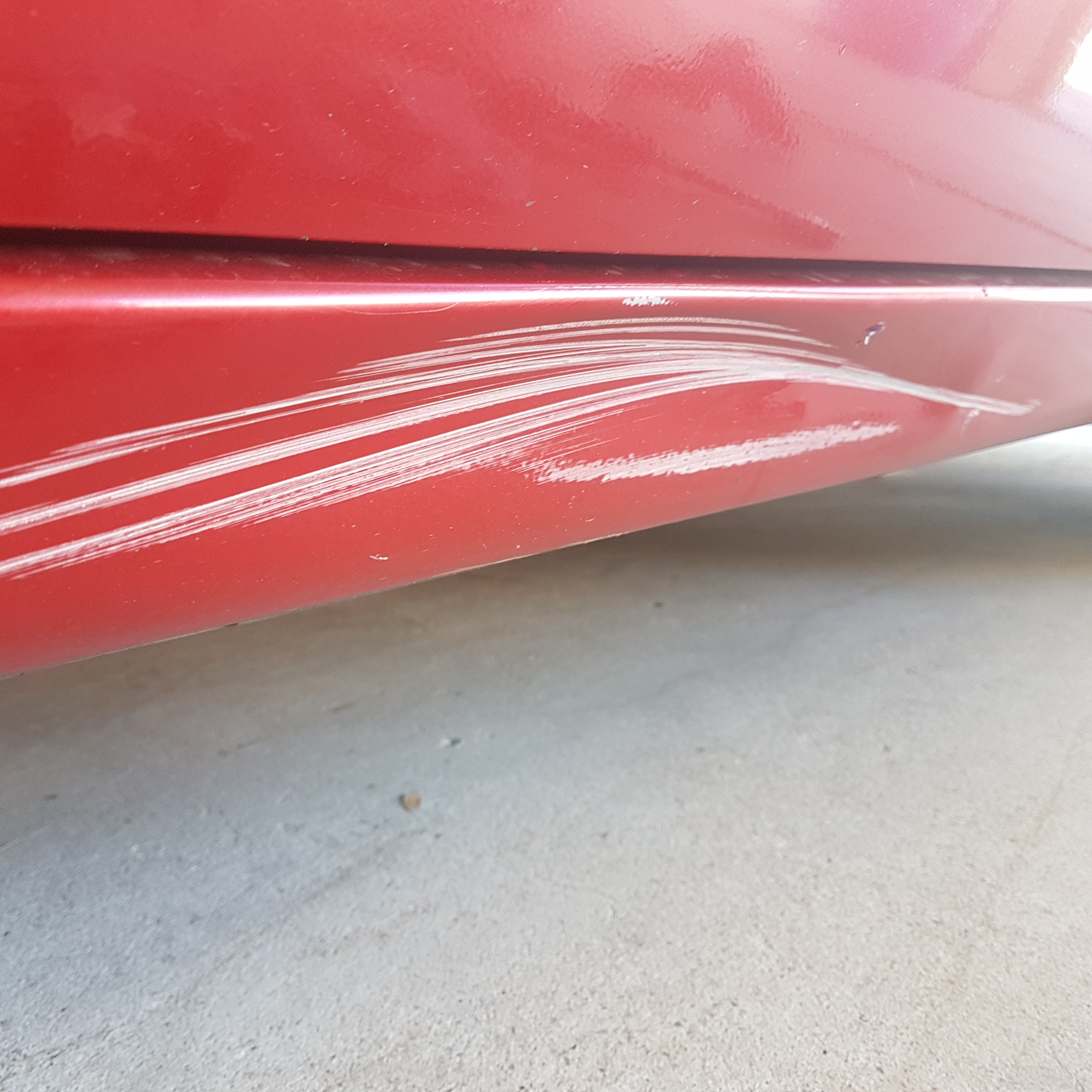 Before photo of red lower door and side skirt scuff damage